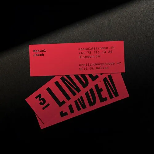 Red business cards on black surface with contact details for Manuel Jakob and bold text '3 LINDEN'.
