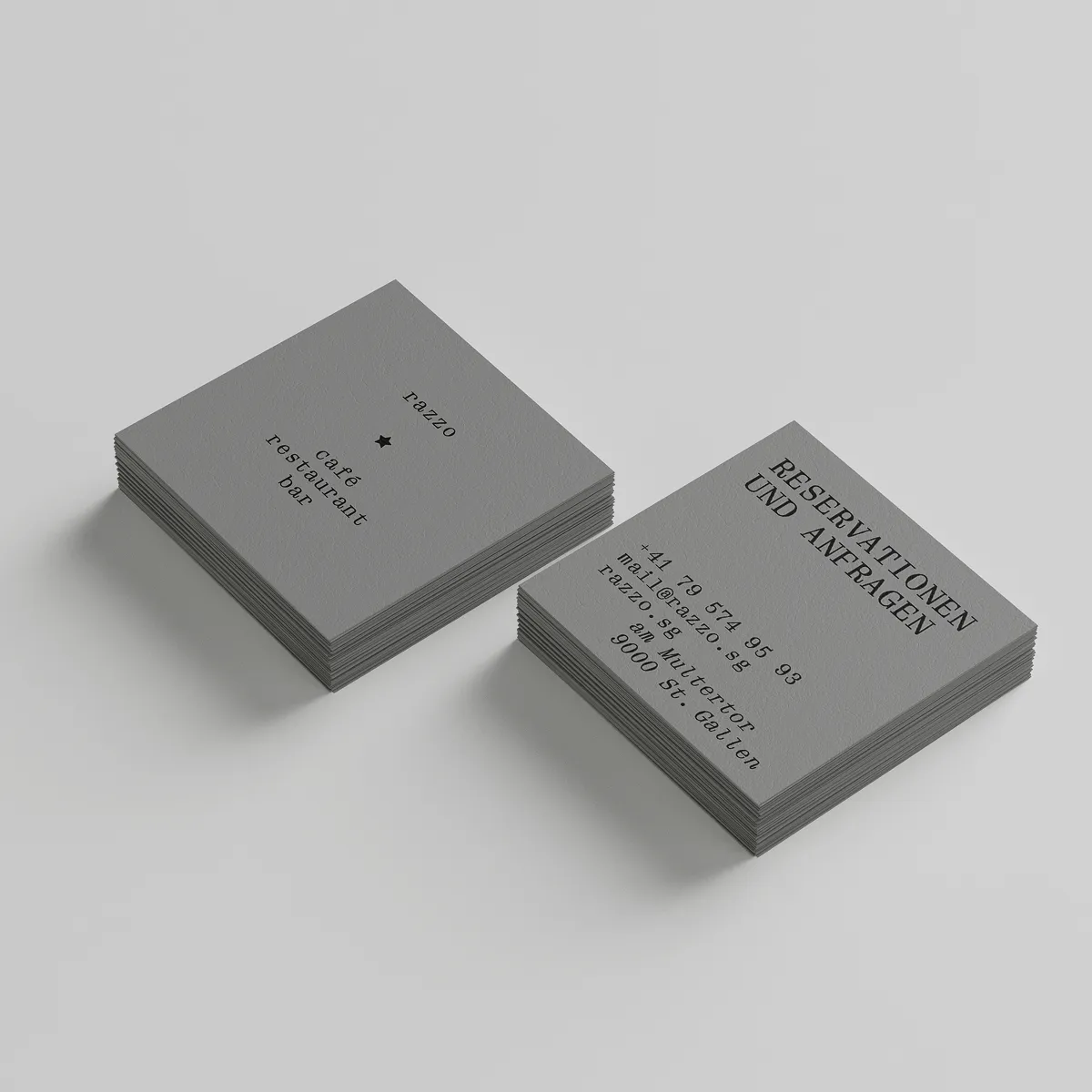 Two stacks of gray business cards for 'Trazzo cafe restaurant bar' displaying contact information and reservation details in black typewriter-style font.