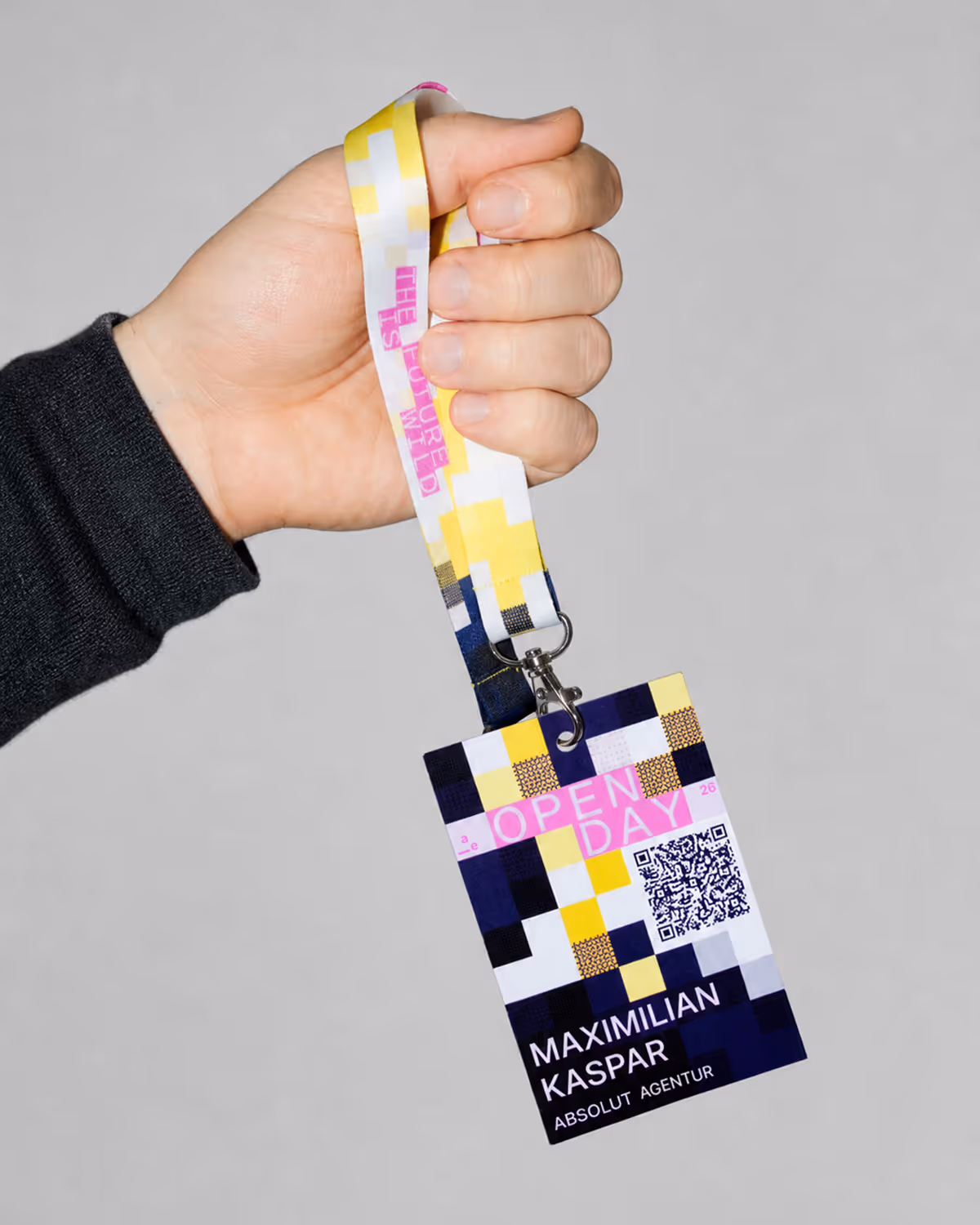 Hand holding event badge with lanyard labeled 'Open Day' and name syxma.