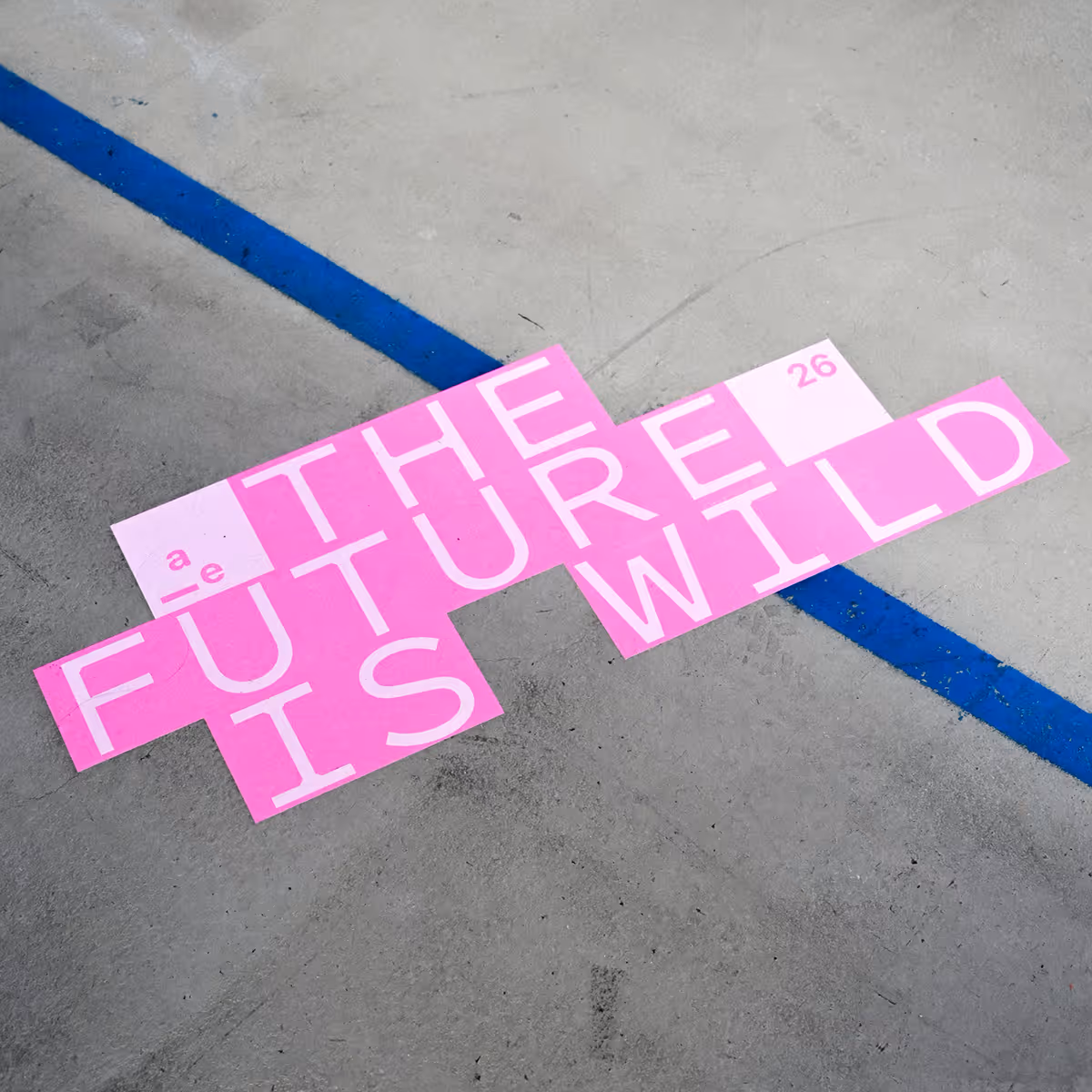 Pink tiles spelling out The Future Is Wired on a gray concrete floor with a blue line.