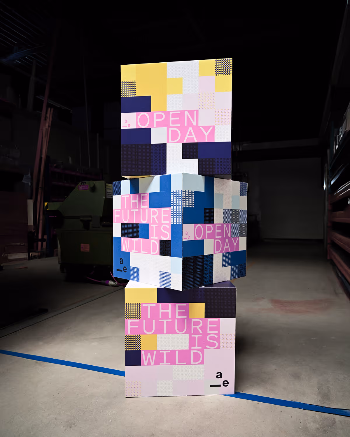 Stacked colorful cubes with text: OPEN DAY and THE FUTURE IS WILD in an industrial setting.