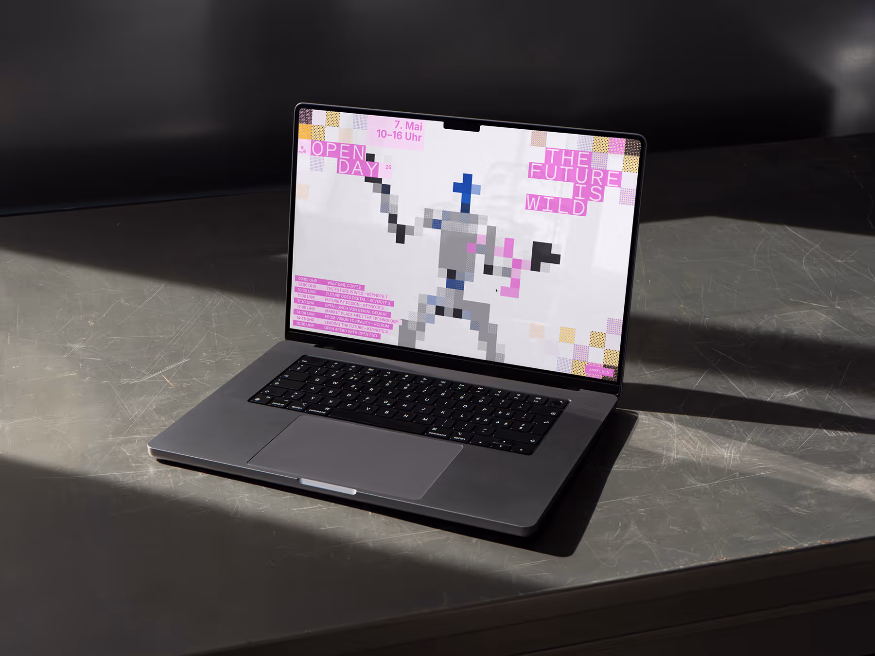 Laptop on a table showing a pixelated figure with text about an open day event on screen.